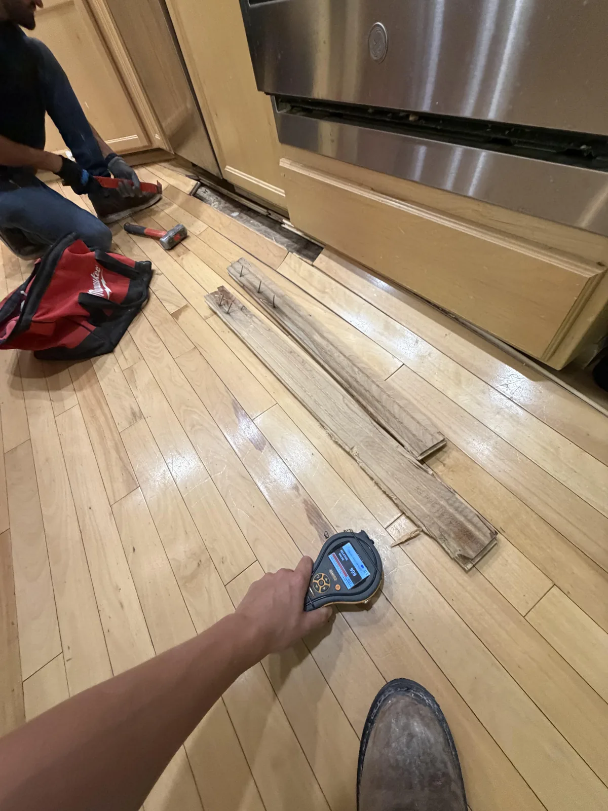 Bothell: Moisture testing beside the dishwasher after targeted removal of warped hardwood.